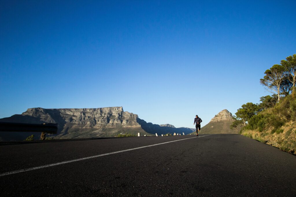 a person running on a road with mountains in the background